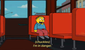 Ralph from The Simpsons, a child, sitting in a bus seat chuckling to himself "I'm in danger."